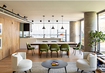 Fotografia de um ambiente interno com janelas grandes, móveis de sala de jantar e piso de madeira.